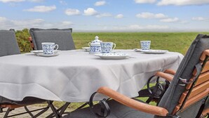 An outdoor dining setup with a table set for four, featuring blue and white patterned tableware. - SO/10 Söl`ring Hüs Raantem Lek - Söl'ring Hüs (Sylt)