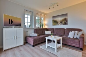 Un salon avec un ensemble de canapés marron, une table basse blanche, un meuble blanc et un tableau accroché au mur.