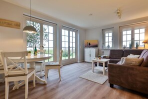 A spacious living area with a dining table, chairs, a sofa, and a TV. - SO/10 Söl`ring Hüs Raantem Lek - Söl'ring Hüs (Sylt)