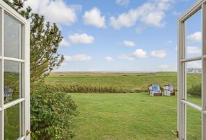 A view from a window overlooking a grassy field with two beach chairs and a distant horizon. - SO/10 Söl`ring Hüs Raantem Lek - Söl'ring Hüs (Sylt)