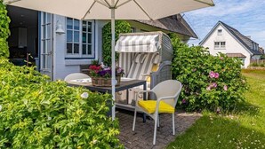 An outdoor patio with a table, chairs, and a large umbrella. - Söl`ring Hüs "Meerblick" SO/06 - Söl'ring Hüs (Sylt)