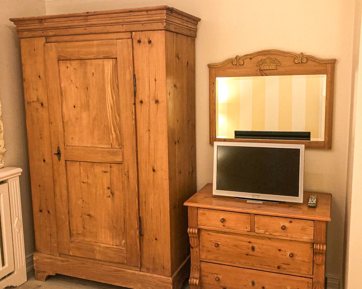 Une armoire en bois avec un miroir et un téléviseur posé sur le dessus.