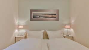 Ett hotellrum med en säng, två sängbord, två lampor och en inramad tavla på väggen.