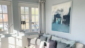 A cozy living room with a beige sofa, a coffee table, and a large abstract painting on the wall.