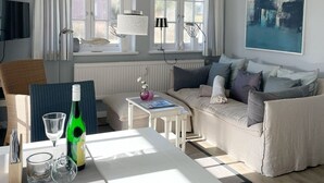 A modern living room with a sofa, a dining table, and a large window.
