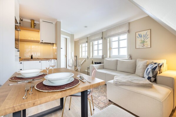 A modern kitchen with a dining area, a sofa, and a window with a view. - Raantem Hüs App. 09 - Raantem Hus (Sylt)