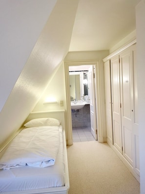 Ein Schlafzimmer mit Bett, ein Badezimmer mit Waschbecken und Spiegel sowie ein Kleiderschrank.