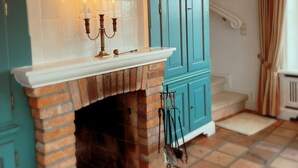 Une pièce avec une cheminée en briques, des meubles de couleur turquoise et un escalier.