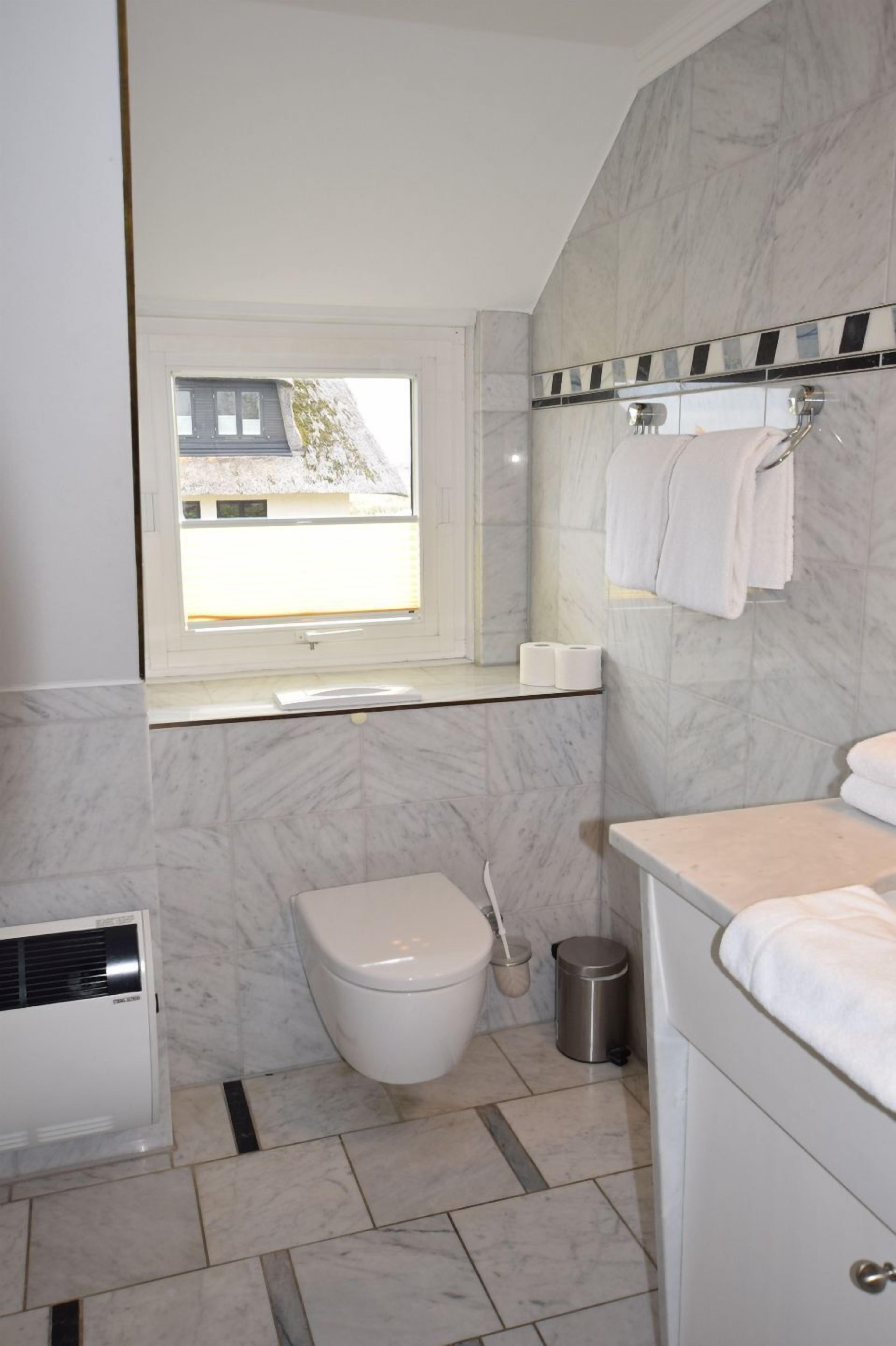 A bathroom with a toilet, sink, and window.