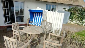 A patio with a round wooden table and six wooden chairs. - House Wattblick App. 03 - Wattblick (Sylt)
