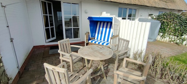 A patio with a round wooden table and six wooden chairs. - House Wattblick App. 03 - Wattblick (Sylt)