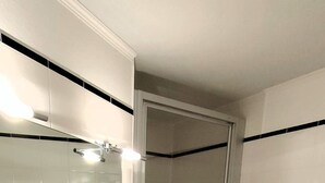 A bathroom with a white sink, a glass shelf, a mirror, and a shower area. - House Wattblick App. 03 - Wattblick (Sylt)