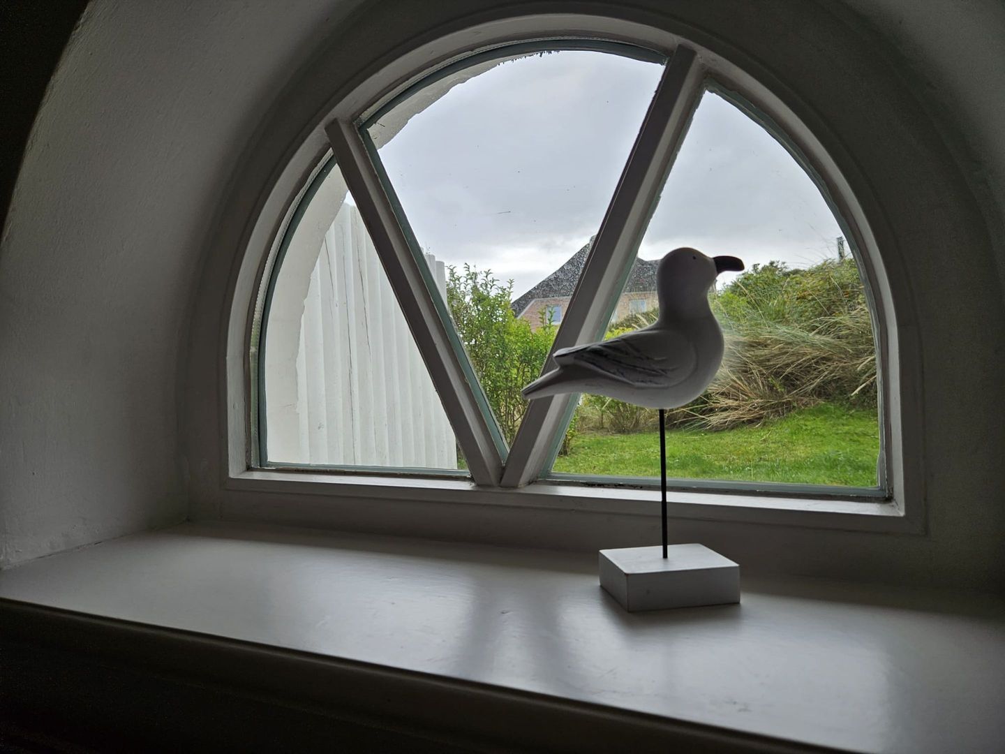 A bird figurine on a window ledge.
