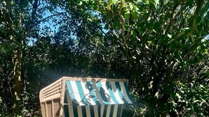 Ein Korbstuhl mit gestreiften Kissen in einem Garten.