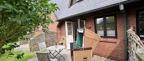A patio with a table and chairs, a wicker chair, and a green chair.