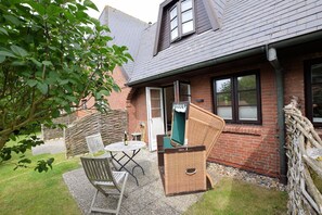 A patio with a table and chairs, a wicker chair, and a green chair.