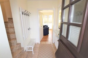 A hallway with a bench, a coat rack, and a door with a window. - Landhaus Ruusenhüs App. Ruu 05 - Landhaus Ruusenhüs (Sylt)