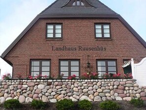 A brick building with the name "Landhaus Ruusenshuis" on the facade.