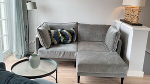 Una sala de estar moderna con un sofá seccional gris, una mesa de centro redonda y una lámpara de pie.