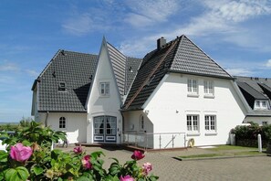 A large, white, two-story house with a steeply pitched roof and a small tower-like structure.