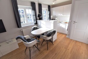 A modern kitchen with white cabinets, a dining table, and two chairs.