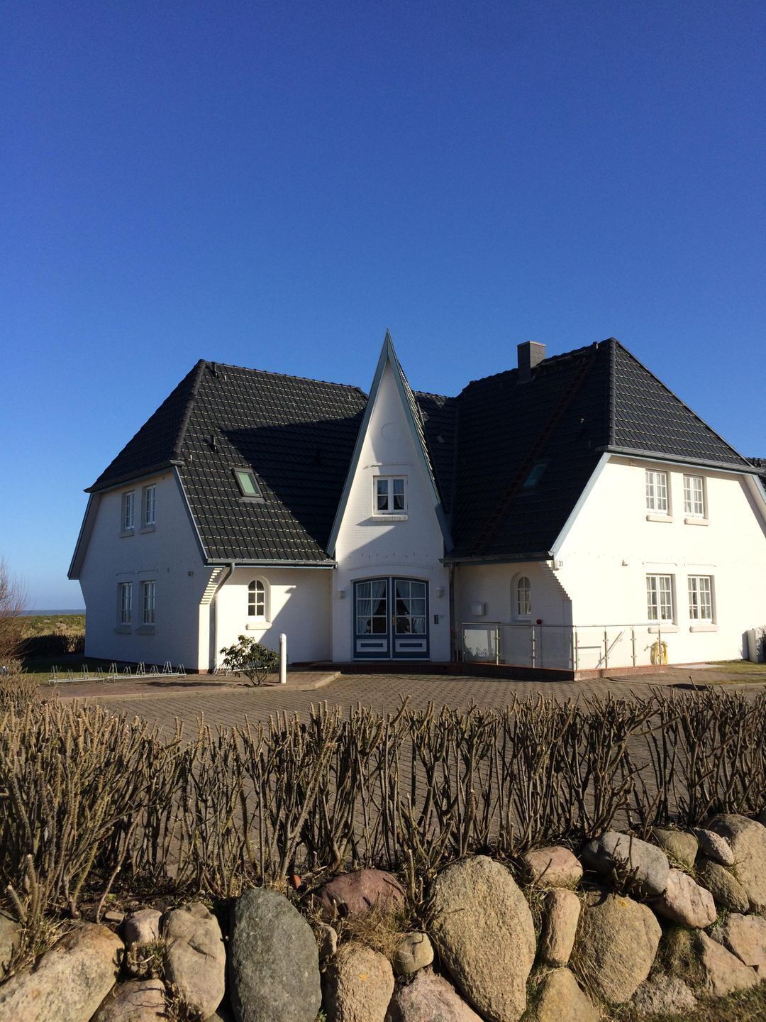A large, white house with a steeply pitched roof and a symmetrical facade.