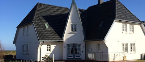 Ein großes, weißes Haus mit steilem Dach und einer symmetrischen Vorderseite.