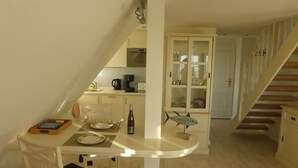 Una cocina compacta con comedor, una escalera y un armario con puertas de vidrio.