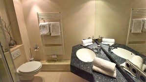A modern bathroom with a dual sink vanity, a toilet, and a towel rack.