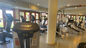 Un gimnasio con equipos de ejercicio variados, incluyendo cintas de correr, una escaladora y máquinas de pesas.