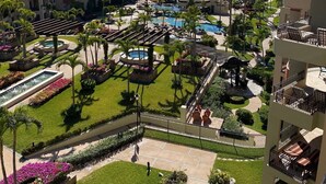 Un resort con varias piscinas, palmeras y vista al océano.