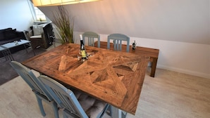 Un comedor con una mesa de madera, cuatro sillas, una botella de vino y una lámpara.