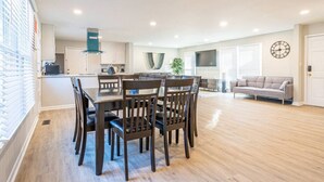 Amplia sala de estar con una mesa de comedor y sillas, un sofá y un televisor.
