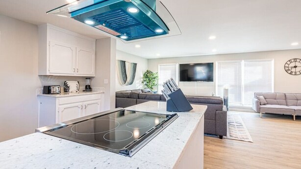 Cocina moderna con una isla central, armarios blancos y una campana extractora azul.