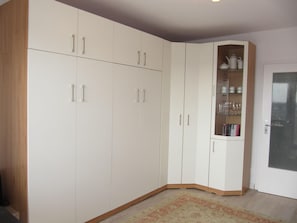 Une pièce dotée d’une grande armoire, d’un meuble encastré avec des portes en verre et d’une porte avec un panneau en verre dépoli.