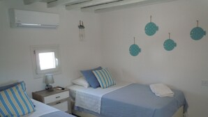 Een slaapkamer met twee bedden, een nachtkastje, een lamp en decoratieve muurkunst van vissen.
