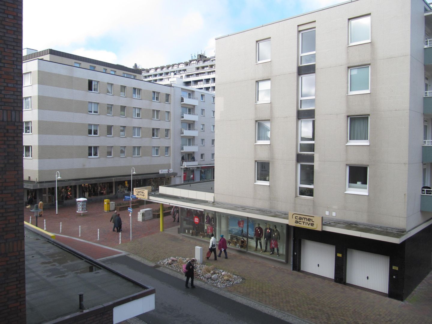 A multi-story building with a ground-level retail space and a parking area.