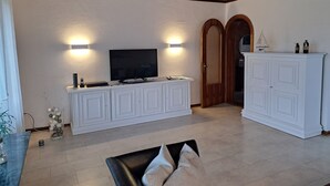 A living room with a flat-screen TV, white cabinetry, and a wooden ceiling. - house Bismarckstr. 40 apartments 40 - 3 room apartment with a beautiful terrace. (Sylt)