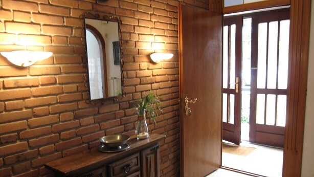 A room with a brick wall, a wooden cabinet, a mirror, and a door with glass panels. - house Bismarckstr. 40 apartments 40 - 3 room apartment with a beautiful terrace. (Sylt)