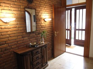 Une pièce avec un mur en briques, une armoire en bois, un miroir et une porte à panneaux de verre.
