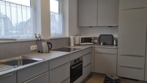 A compact kitchen with a sink, stove, microwave, and cabinets. - house Bismarckstr. 40 apartments 40 - 3 room apartment with a beautiful terrace. (Sylt)