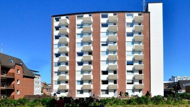 A multi-story building with a curved facade, featuring balconies on each floor.