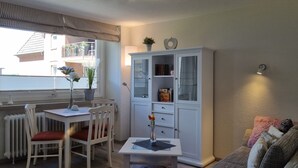 A dining area with a table and chairs, a cabinet with glass doors, and a window with blinds.