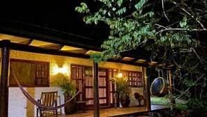 A rustic building with a stone foundation, wooden porch, and a hammock.