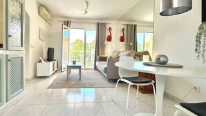 A modern living room with a sofa, a dining table, and a TV. There is a balcony with a view of the outside. - Beach house 2 Palmeras with pool in Port Pollensa (Port de Pollença)