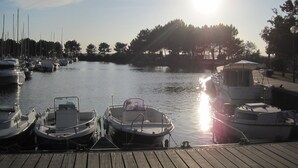 A marina with several boats docked, a wooden pier, and a clear sky with the sun shining. - Single-storey villa, large plot, close to lake and ocean (Hourtin)