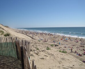 A beach with a wooden fence and a sandy area with umbrellas and people. - Single-storey villa, large plot, close to lake and ocean (Hourtin)