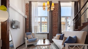 A cozy living room with a white sofa, a wooden coffee table, and a blue armchair. - Cozy Studios on Freedom Square (Tbilisi)
