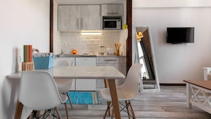 A compact kitchen with white cabinets, a microwave, and a TV mounted on the wall. - Cozy Studios on Freedom Square (Tbilisi)