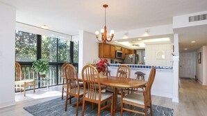 Uma cozinha moderna com armários de madeira, uma mesa de jantar com cadeiras e uma janela grande com vista para o verde.